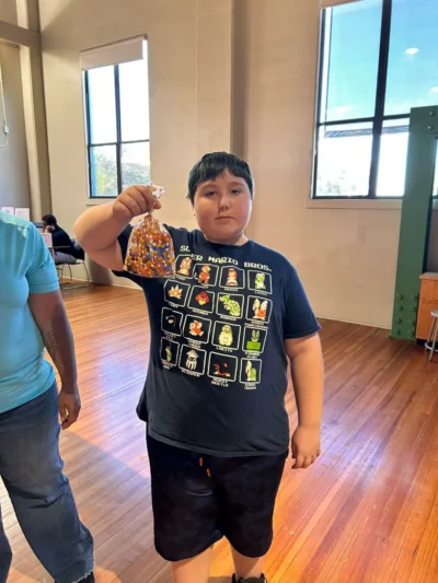 A young person stands indoors on a wooden floor