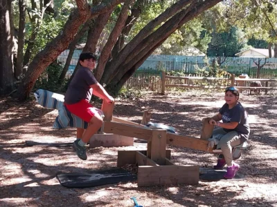 Two children playing on a seesaw in a sunlit park