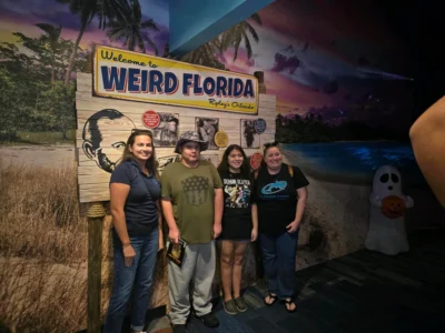 A group of four people poses in front of a "Welcome to Weird Florida" sign at Ripley's Orlando.