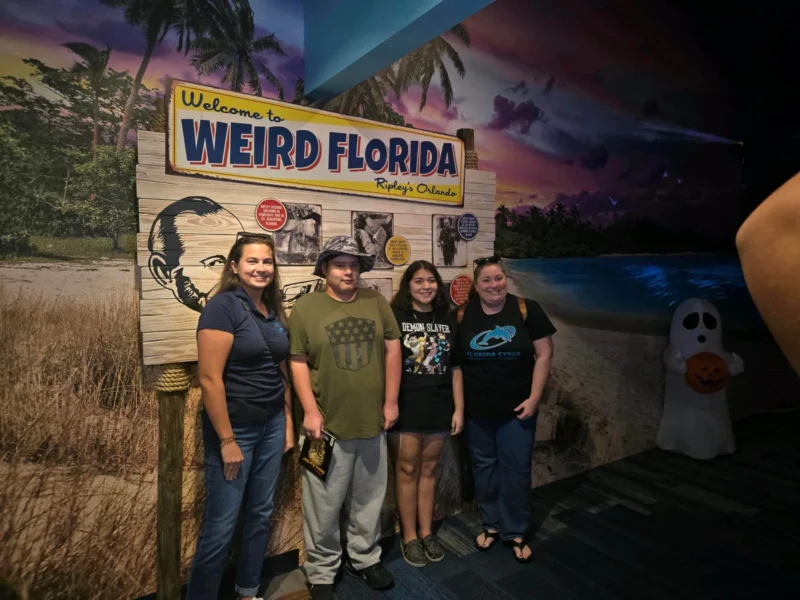 A group of four people poses in front of a "Welcome to Weird Florida" sign at Ripley's Orlando.
